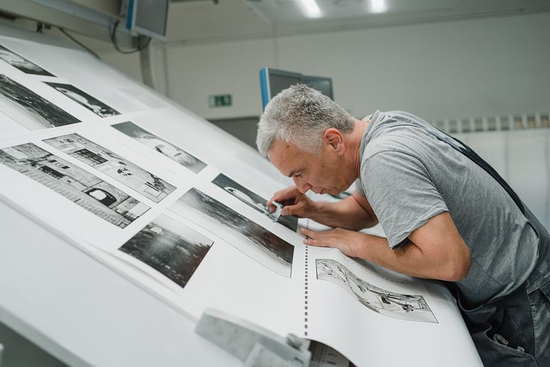 Mitarbeiter in einer Stuttgarter Druckerei bei der Qualitätskontrolle eines Druckbogens – Businessfotografie von Kai Schwab